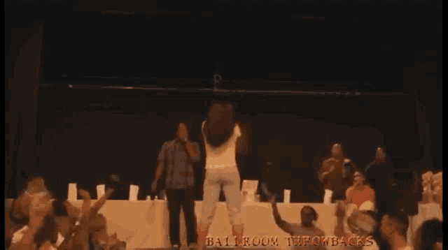 a man singing into a microphone in front of a crowd with the words ballroom throwbacks in red