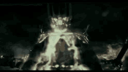 a person with a crown on their head is surrounded by flames in a dark room .