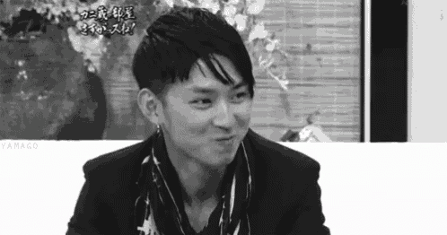 a black and white photo of a man in a suit making a funny face .
