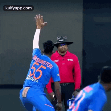 a man in a blue shirt with the number 55 on it is throwing a cricket ball .