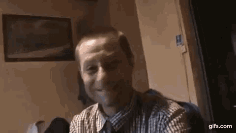 a man in a plaid shirt is smiling and making a funny face .
