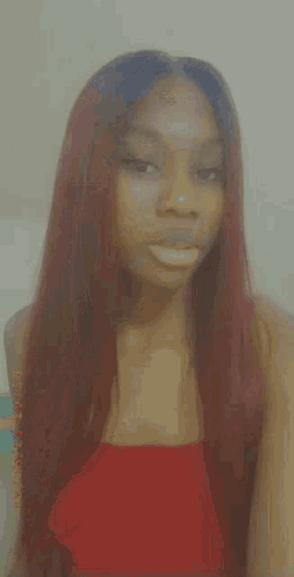 a woman with long red hair and a red top is taking a selfie .
