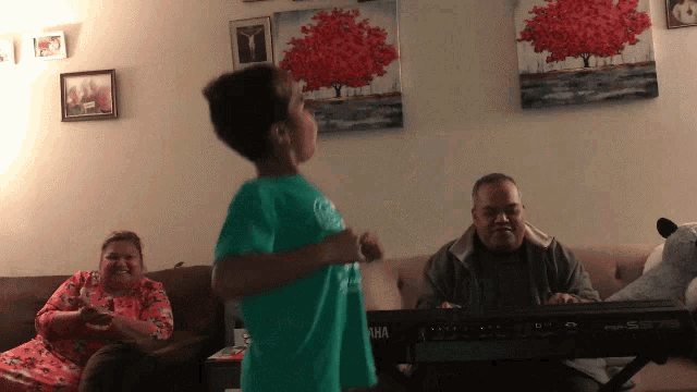a boy in a green shirt is dancing in front of a keyboard that says yamaha