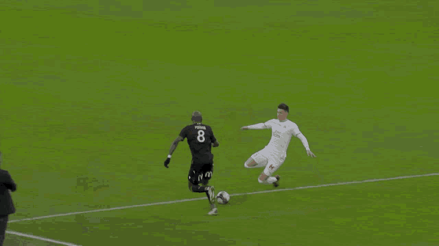 a man in a suit stands on a soccer field next to a player wearing a white shirt that says new balance