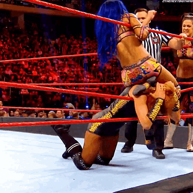 a woman with blue hair is holding a man in a wrestling ring