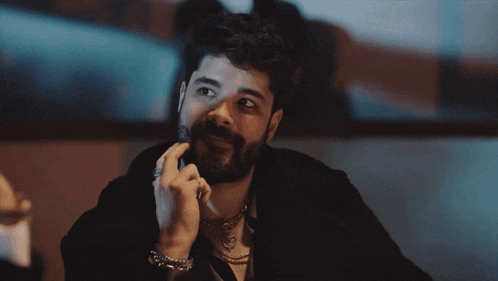 a man with a beard is wearing a gold necklace