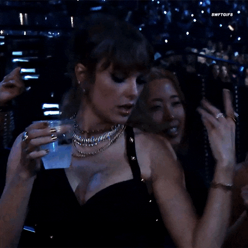 a woman in a black dress is holding a glass of water ..