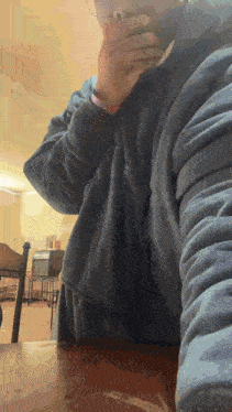 a person sitting at a table with their hands on their chin