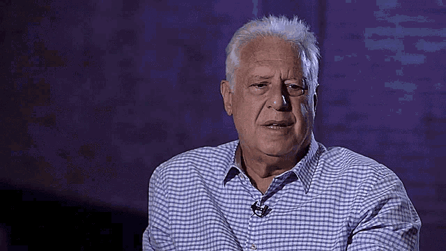 an older man wearing a blue and white checkered shirt