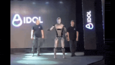 a robot is dancing on a stage in front of an idol sign