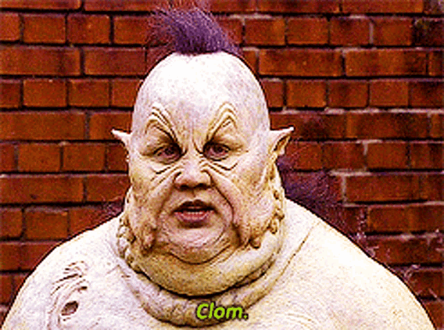 a statue of a man with a mohawk and the word clom written on his chest