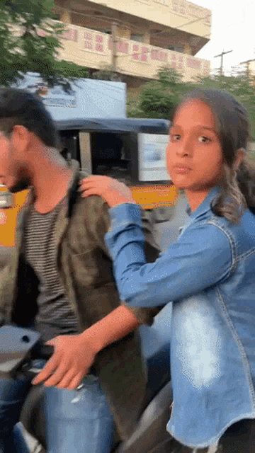 a man and a girl are riding a motorcycle in front of a building that says ' shree ram '