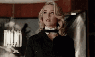 a woman in a tuxedo and bow tie is standing in a room .