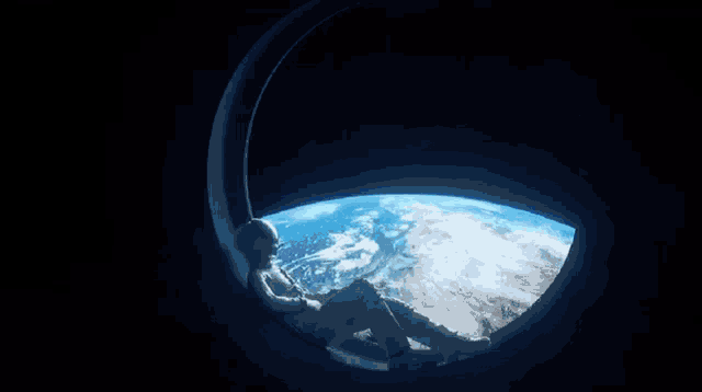 a man in a space suit looks out a window at the earth