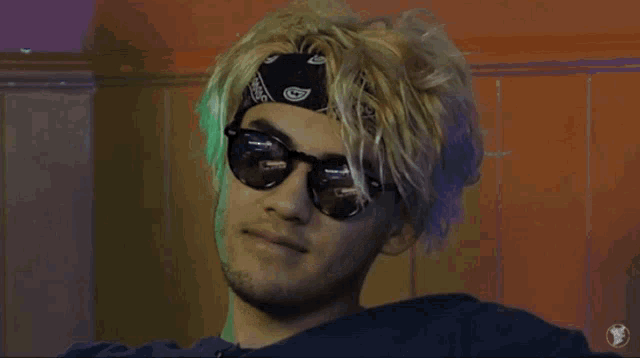 a man wearing sunglasses and a bandana has a reflection of himself in the glasses