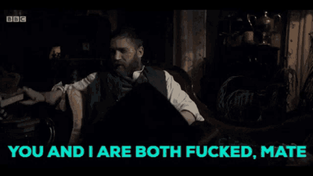a man with a beard sits in a chair with the words " you and i are both fucked mate " below him