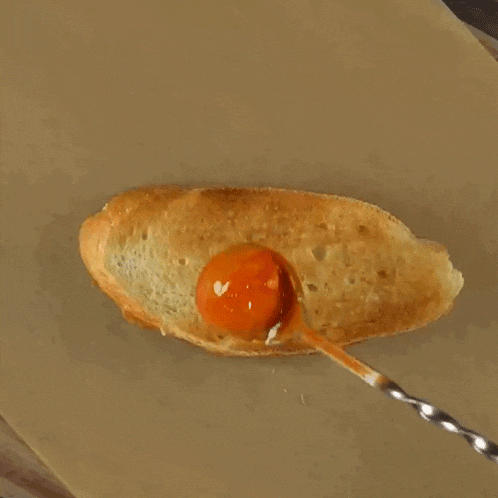a spoon is dipping a piece of bread into a sauce .