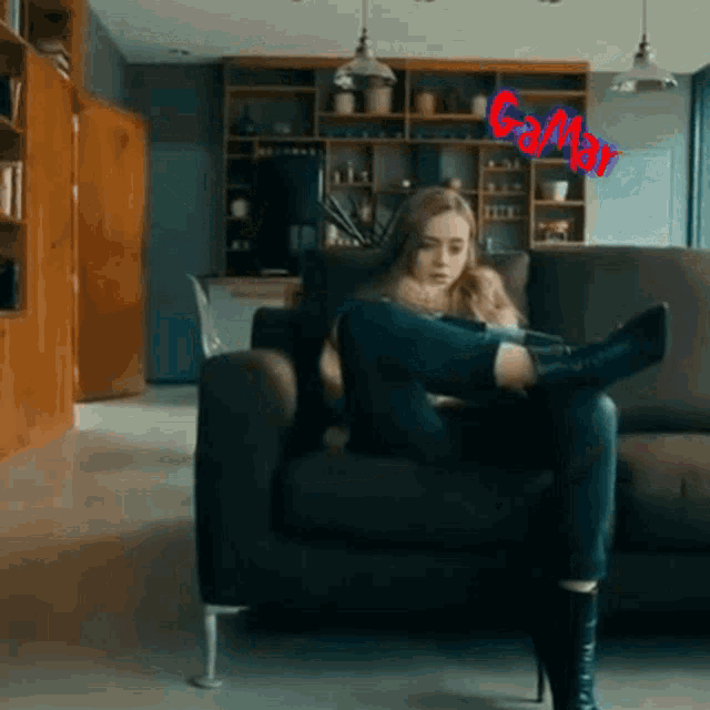 a woman is sitting on a couch with her legs crossed and a red sign that says gamba