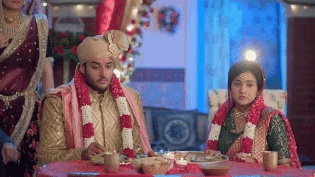 a bride and groom are sitting at a table with a plate of food