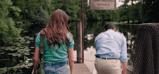 a man and woman standing on a dock near a sign that says jumpin 's