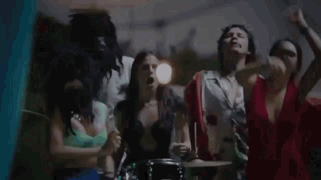 a group of people are standing around a drum set and playing drums .