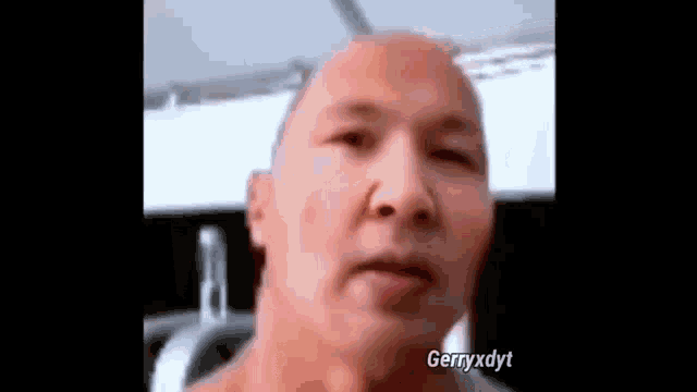 a close up of a man 's face with a bald head in a gym .