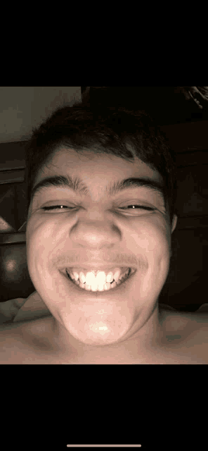 a young man with braces on his teeth is smiling with his eyes closed