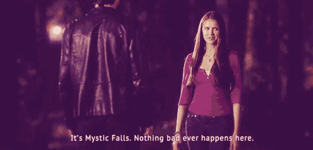a woman in a purple shirt stands next to a man in a black jacket and says it 's mystic