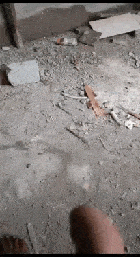 a person is standing on a dirt floor in a room with a lot of junk on it .