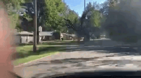 a car is driving down a street in a residential area with smoke coming out of the windshield .