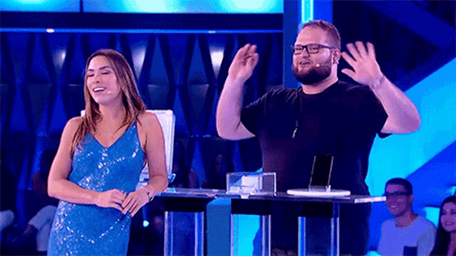 a man and a woman are standing next to each other on a stage in front of a microphone .