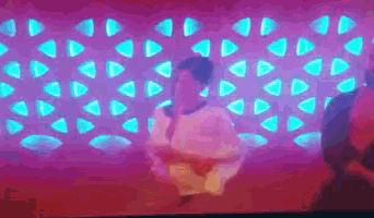 a man is sitting in front of a purple wall with blue triangles .