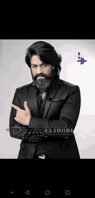 a man with a beard is wearing a black suit and pointing his finger .