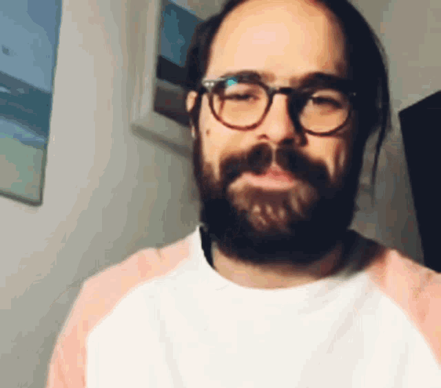 a man with glasses and a beard is wearing a pink and white shirt