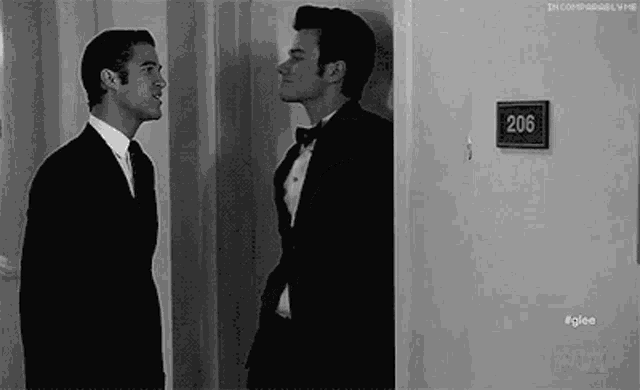 two men in suits and bow ties are standing next to each other in a room .