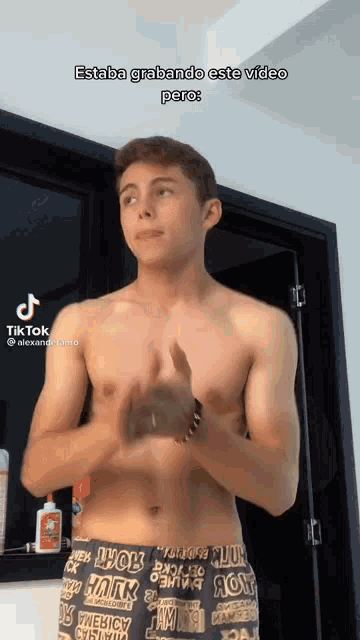 a young man without a shirt is standing in front of a door with his hands in his pockets .