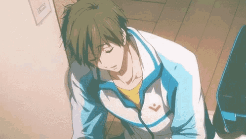 a man in a blue and white jacket is sitting on the floor .