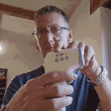 a man with glasses is holding a thermometer in his hands