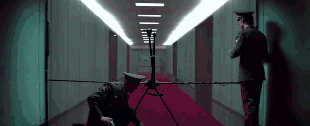 two men in military uniforms are standing in a long hallway