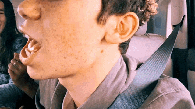 a close up of a person 's face with a seat belt around their neck