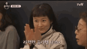 a woman is clapping her hands while sitting next to another woman in a restaurant .