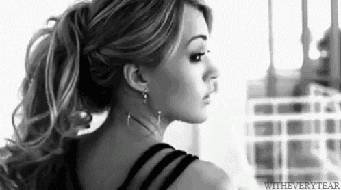 a black and white photo of a woman with long hair in a ponytail .