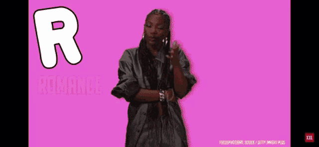 a woman in a black robe is standing in front of a pink background with the letter r on it