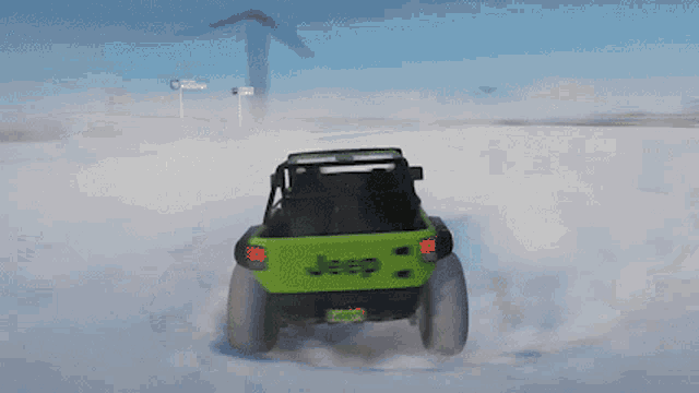 a green jeep is driving through the snow on a cloudy day