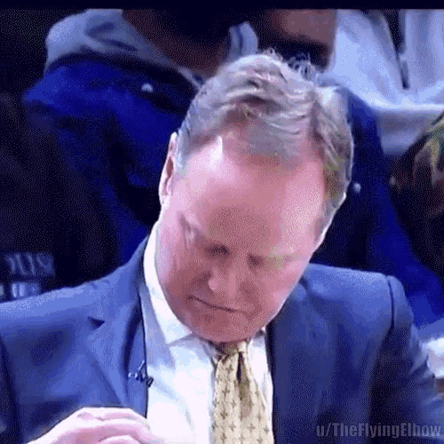 a man in a suit and tie is sitting at a table with his head down