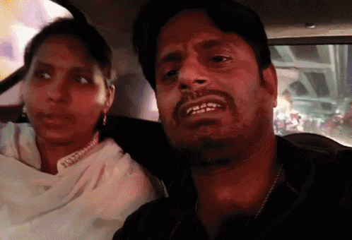 a man and a woman are sitting in a car and the woman is wearing earrings