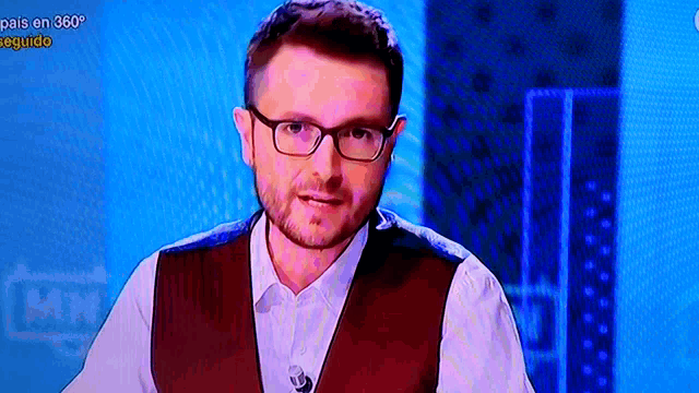 a man wearing glasses stands in front of a blue screen that says pais en 360 degree seguido