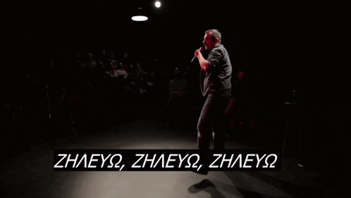 a man singing into a microphone in front of a crowd with the words zhleyq zhleyq zhleyq written below him