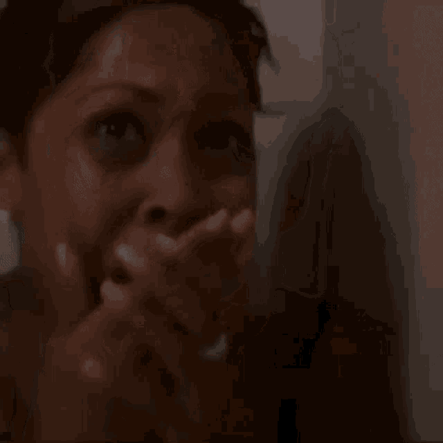 a woman is covering her mouth with her hand and laughing .