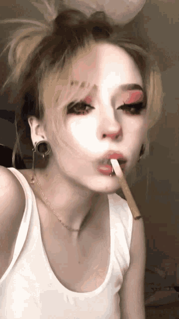 a woman in a white tank top is smoking a cigar